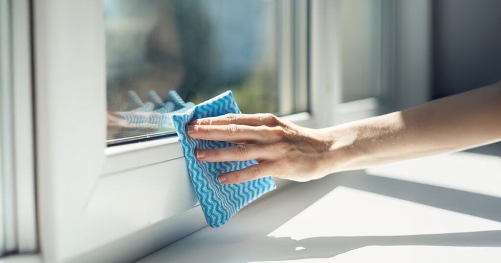 Hand cleaning a white uPVC window frame, showing its low-maintenance design, durability and easy care for modern homes.