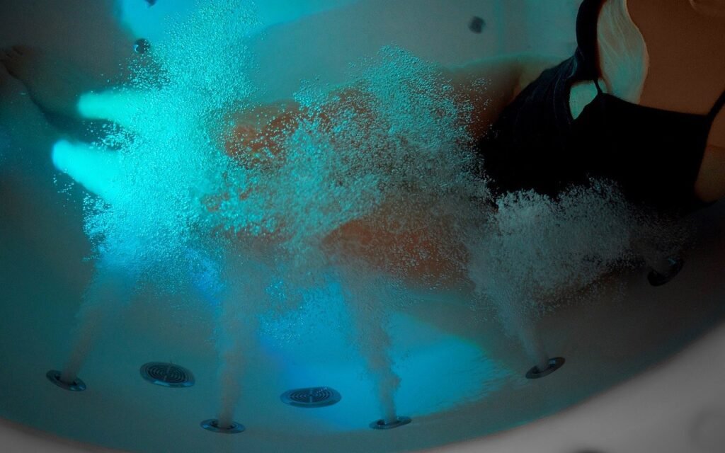 Hydrotherapy whirlpool bathtub with illuminated water jets creating a spa-like massage experience, highlighting whirlpool bath benefits for relaxation, muscle recovery, and luxury home wellness by Oyster Lifestyle.
