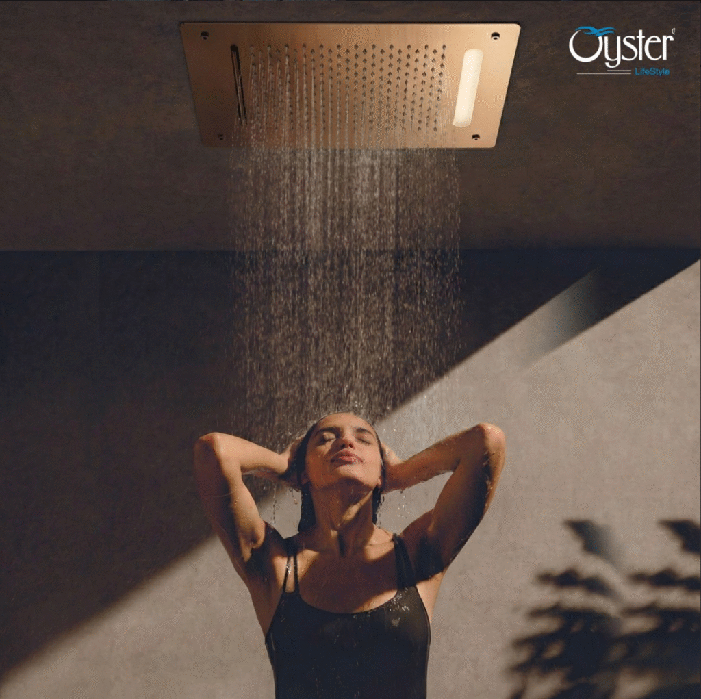 Modern ceiling-installed rain shower panel with integrated lighting and wide rainfall water flow, creating a spa-style shower experience in a contemporary bathroom interior by Oyster Lifestyle.